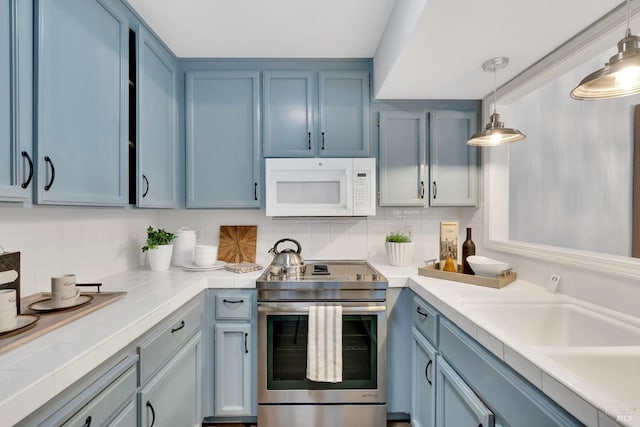 kitchen featuring white microwave, tile counters, decorative backsplash, stainless steel range with electric cooktop, and blue cabinets