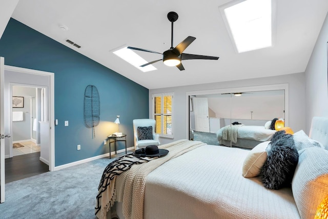 carpeted bedroom featuring lofted ceiling with skylight, visible vents, a ceiling fan, and baseboards