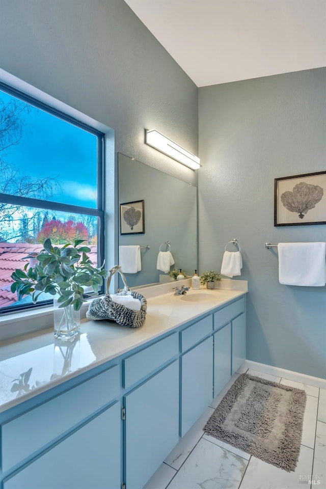 bathroom with double vanity, baseboards, marble finish floor, and a sink