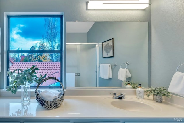 bathroom featuring vanity, a textured wall, and a stall shower