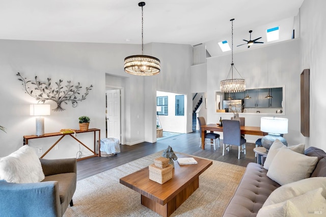 living room featuring stairway, wood finished floors, an inviting chandelier, a skylight, and a high ceiling