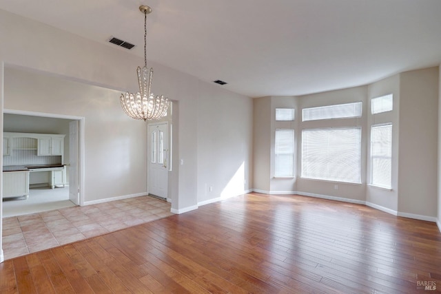 unfurnished room featuring a chandelier and light hardwood / wood-style floors