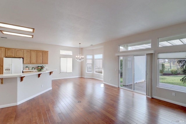 kitchen with white refrigerator with ice dispenser, a kitchen breakfast bar, light hardwood / wood-style floors, and a wealth of natural light