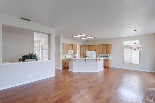 kitchen featuring hardwood / wood-style floors, white appliances, an inviting chandelier, hanging light fixtures, and a kitchen island