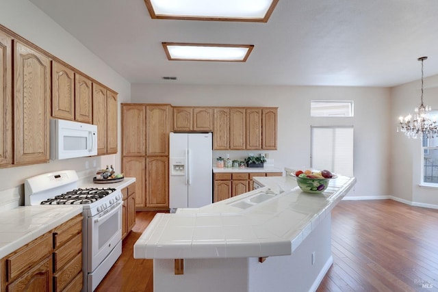 kitchen featuring tile countertops, dark hardwood / wood-style flooring, white appliances, and an island with sink