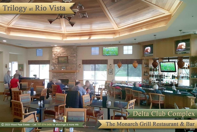 dining room featuring bar area, a raised ceiling, a wealth of natural light, and wood ceiling