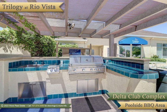 view of swimming pool featuring a pergola, a grill, sink, and an outdoor kitchen