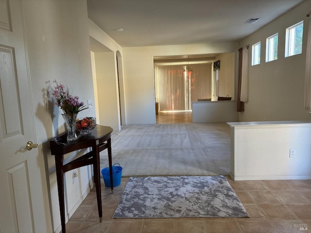 hallway with light carpet and a chandelier