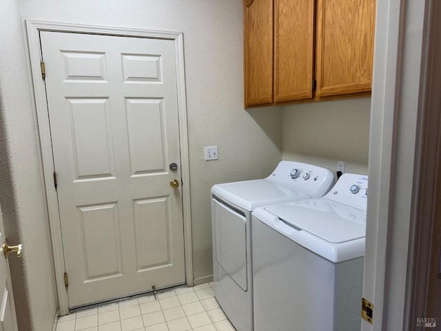 laundry area with cabinets, light tile patterned flooring, and washing machine and clothes dryer