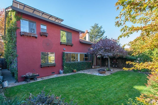 rear view of property with a fire pit and a lawn