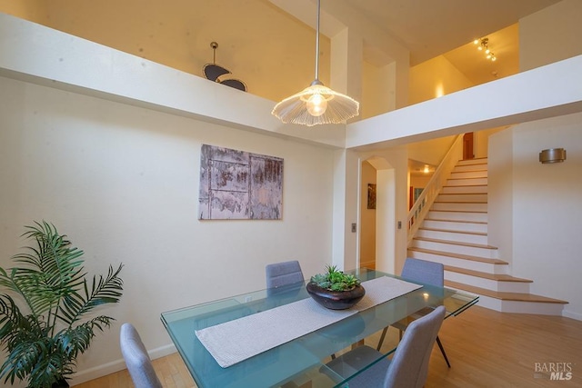 dining space with hardwood / wood-style flooring and a towering ceiling