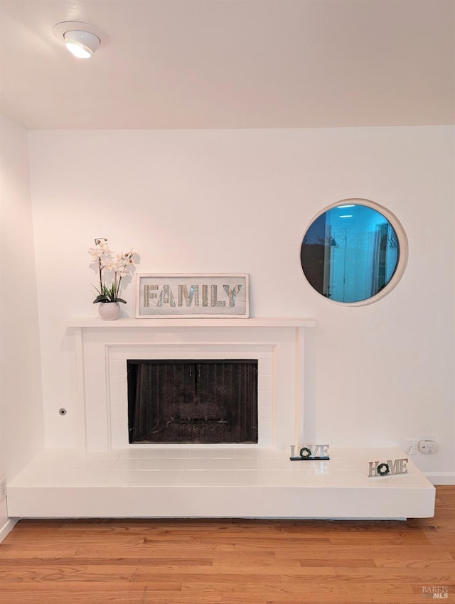 details with a tiled fireplace and wood-type flooring