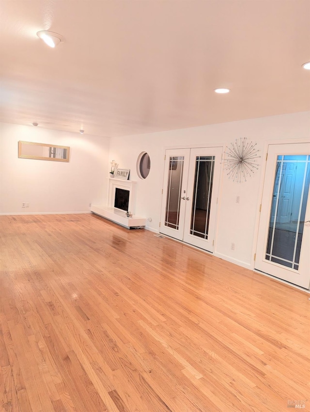 unfurnished living room with french doors and light wood-type flooring