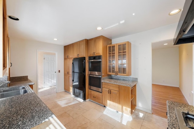 kitchen featuring sink, light tile patterned floors, black refrigerator, dark stone counters, and stainless steel double oven