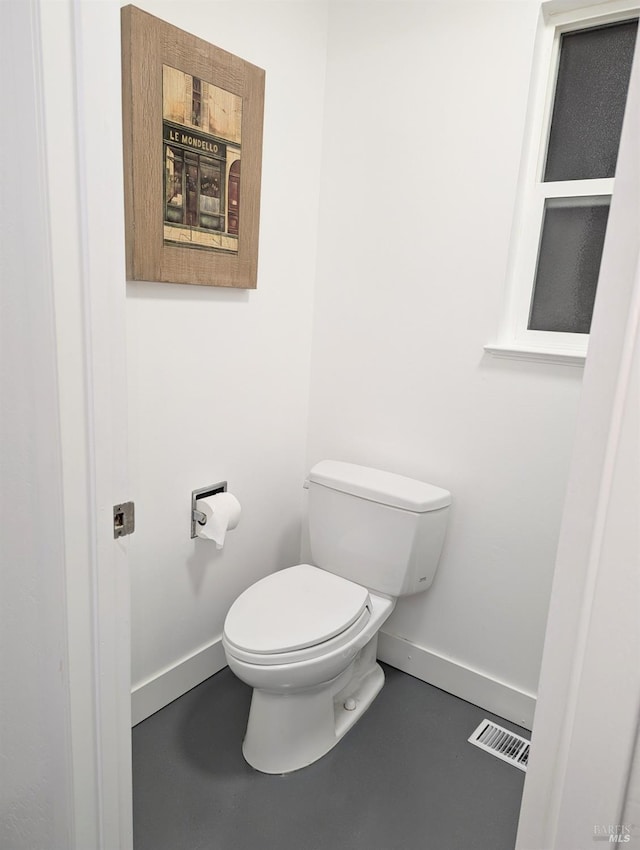 bathroom with concrete flooring and toilet