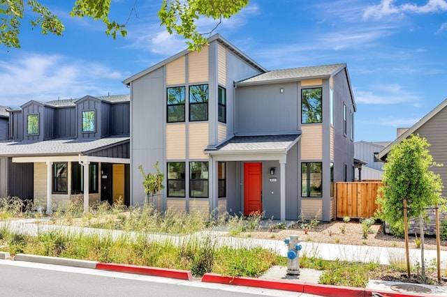 contemporary home featuring roof with shingles and fence