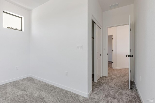 hall with light colored carpet, baseboards, and visible vents