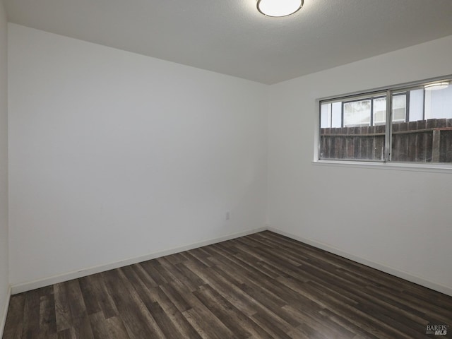 unfurnished room with dark wood-type flooring