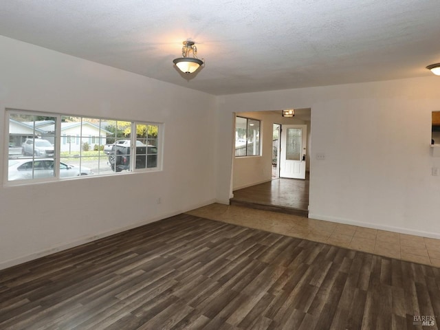 unfurnished room with a textured ceiling and dark hardwood / wood-style flooring