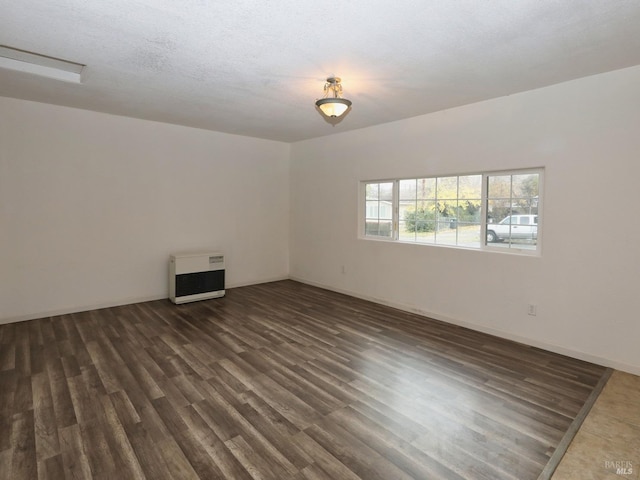 spare room featuring dark hardwood / wood-style flooring, a textured ceiling, and heating unit