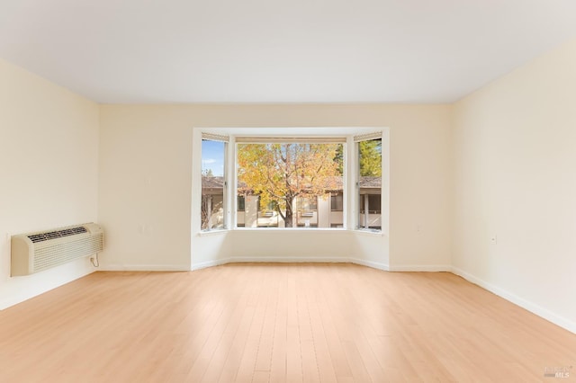 3473 Tice Creek Dr Unit 1, Walnut Creek, CA 94595 - empty room with an AC wall unit, light wood-style flooring, and baseboards
