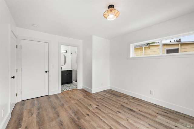 unfurnished bedroom featuring wood-type flooring and connected bathroom