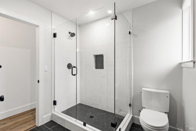 bathroom featuring hardwood / wood-style flooring, toilet, and a shower with door