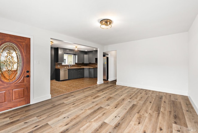 unfurnished living room with sink and light hardwood / wood-style floors