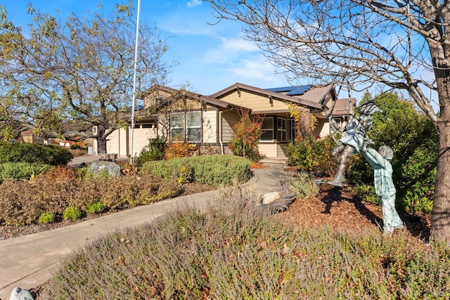 view of front of house with a garage, stone siding, and solar panels