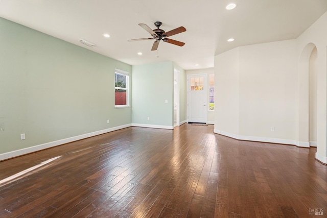 spare room with arched walkways, recessed lighting, baseboards, and wood finished floors