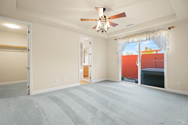 unfurnished bedroom featuring carpet floors, a tray ceiling, access to outside, and visible vents