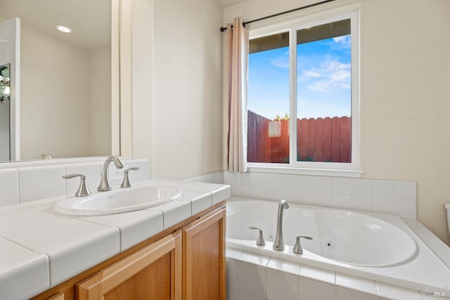 full bathroom with a tub with jets and vanity