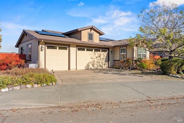 ranch-style home featuring a garage, driveway, and solar panels