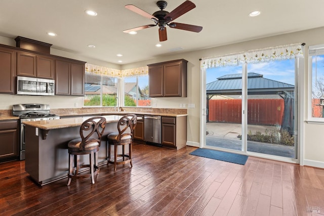 kitchen featuring a breakfast bar, stainless steel appliances, dark wood-type flooring, and recessed lighting