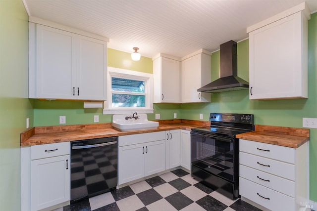 kitchen featuring black appliances, wall chimney range hood, sink, butcher block countertops, and white cabinetry