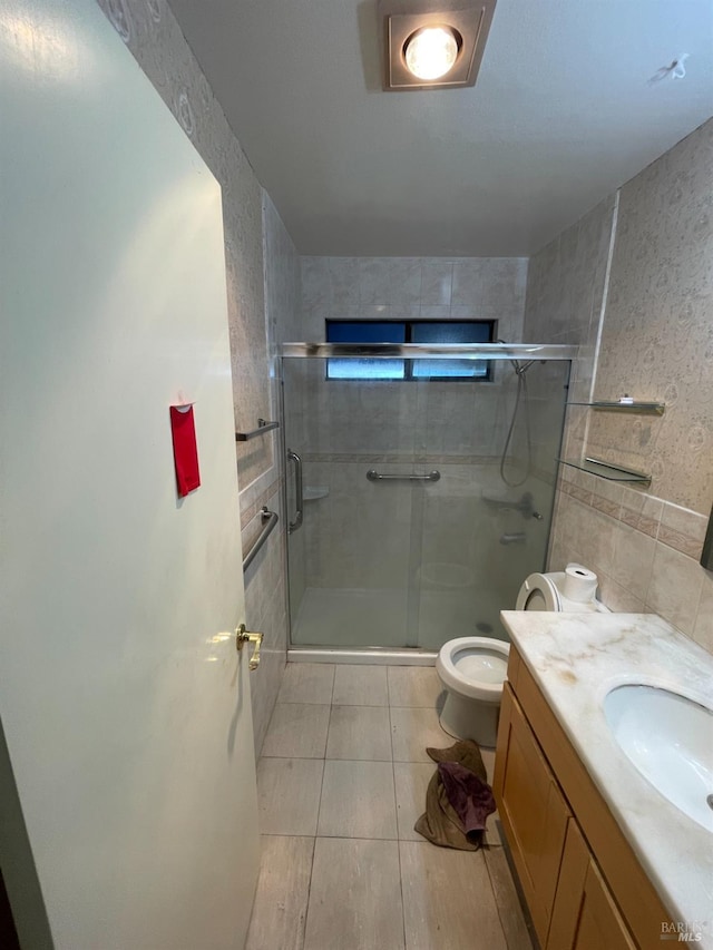 bathroom featuring walk in shower, tile patterned flooring, toilet, vanity, and tile walls