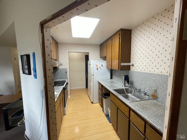 kitchen featuring sink, a skylight, light hardwood / wood-style flooring, stainless steel electric range oven, and white fridge