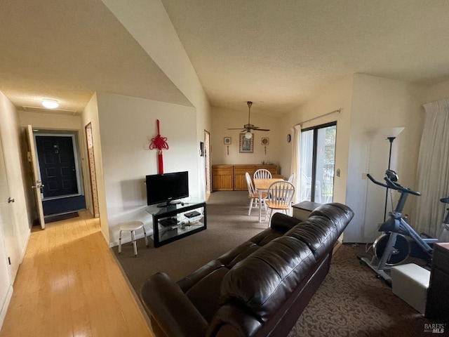 living room with ceiling fan, light hardwood / wood-style floors, a textured ceiling, and vaulted ceiling