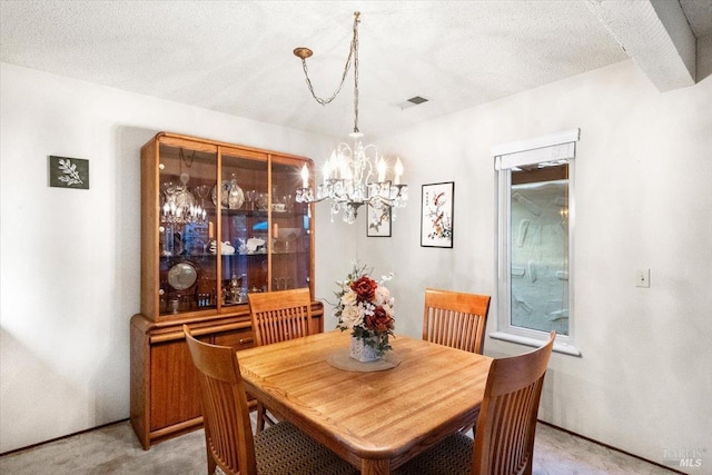 dining room featuring carpet, a textured ceiling, and a chandelier