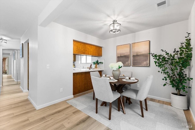 dining area featuring light wood-style floors, visible vents, a notable chandelier, and baseboards