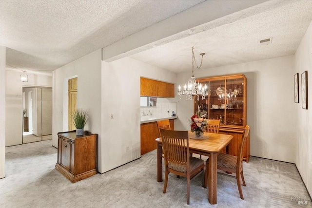 dining area featuring light colored carpet, a textured ceiling, and an inviting chandelier