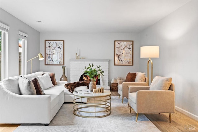 living room with baseboards, a fireplace, visible vents, and wood finished floors