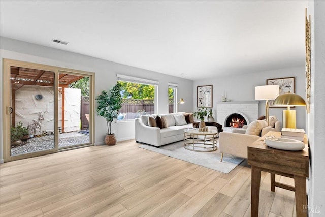 living area with a fireplace, visible vents, and wood finished floors