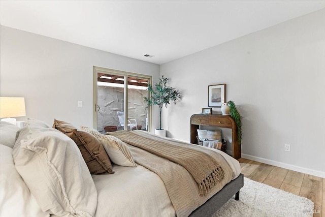 bedroom with baseboards, access to outside, visible vents, and wood finished floors