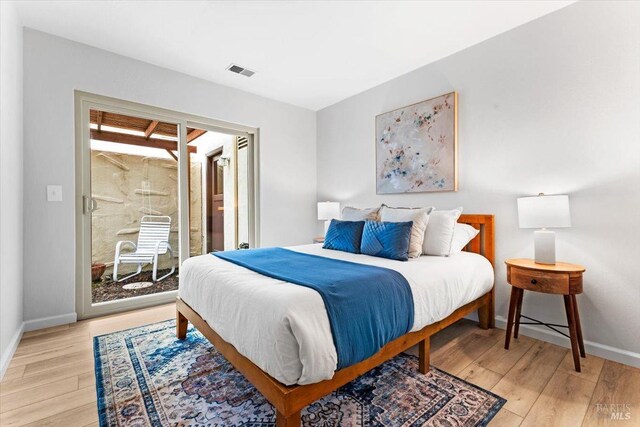 bedroom featuring light wood-type flooring, access to outside, visible vents, and baseboards