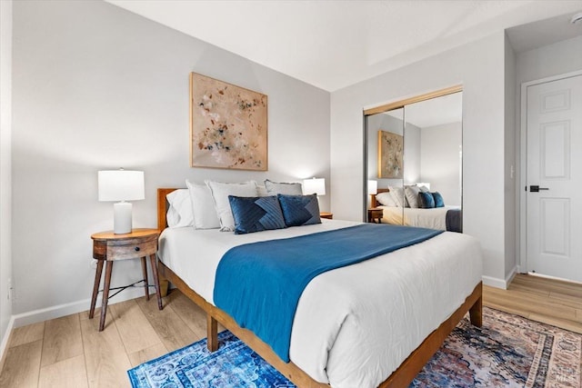 bedroom featuring light wood finished floors, a closet, and baseboards