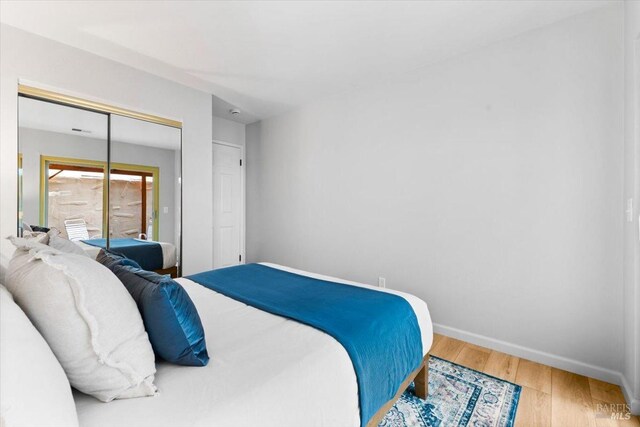 bedroom with a closet, baseboards, and wood finished floors