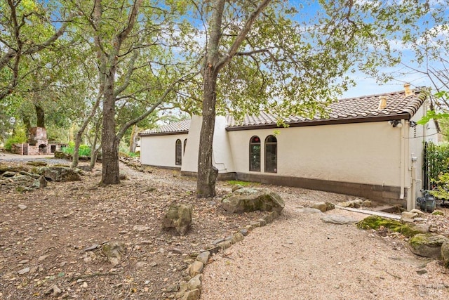 back of house with a tile roof and stucco siding