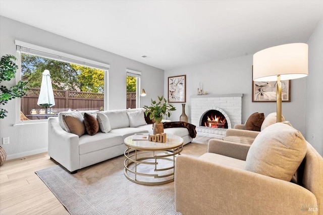 living room with light wood-type flooring, a fireplace, and baseboards