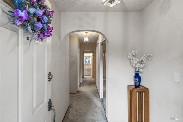 corridor with light colored carpet and a textured ceiling